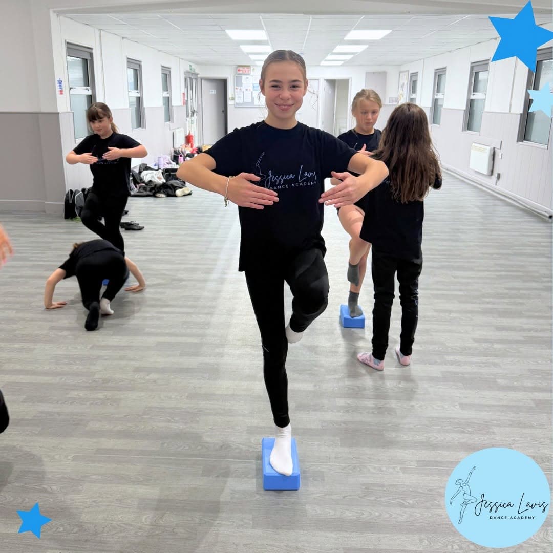 A young dancer balancing on a foam block during a technique exercise