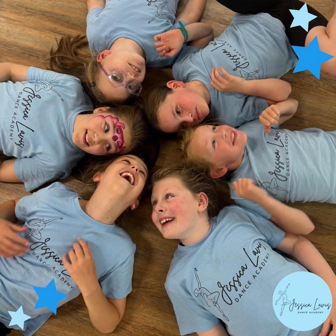 Six dancers lying on the floor in a circle, laughing together