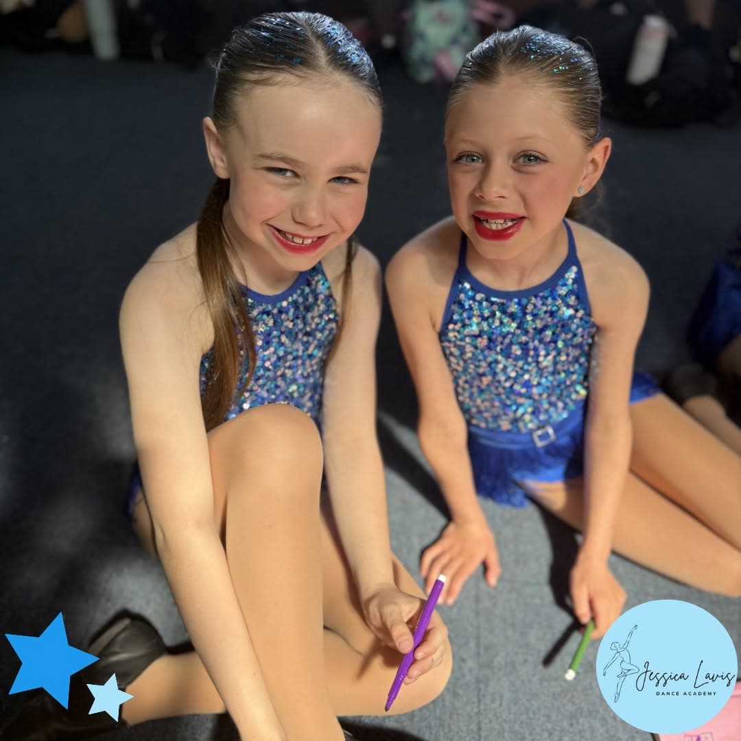 Two young dancers relaxing backstage with colouring pens between numbers
