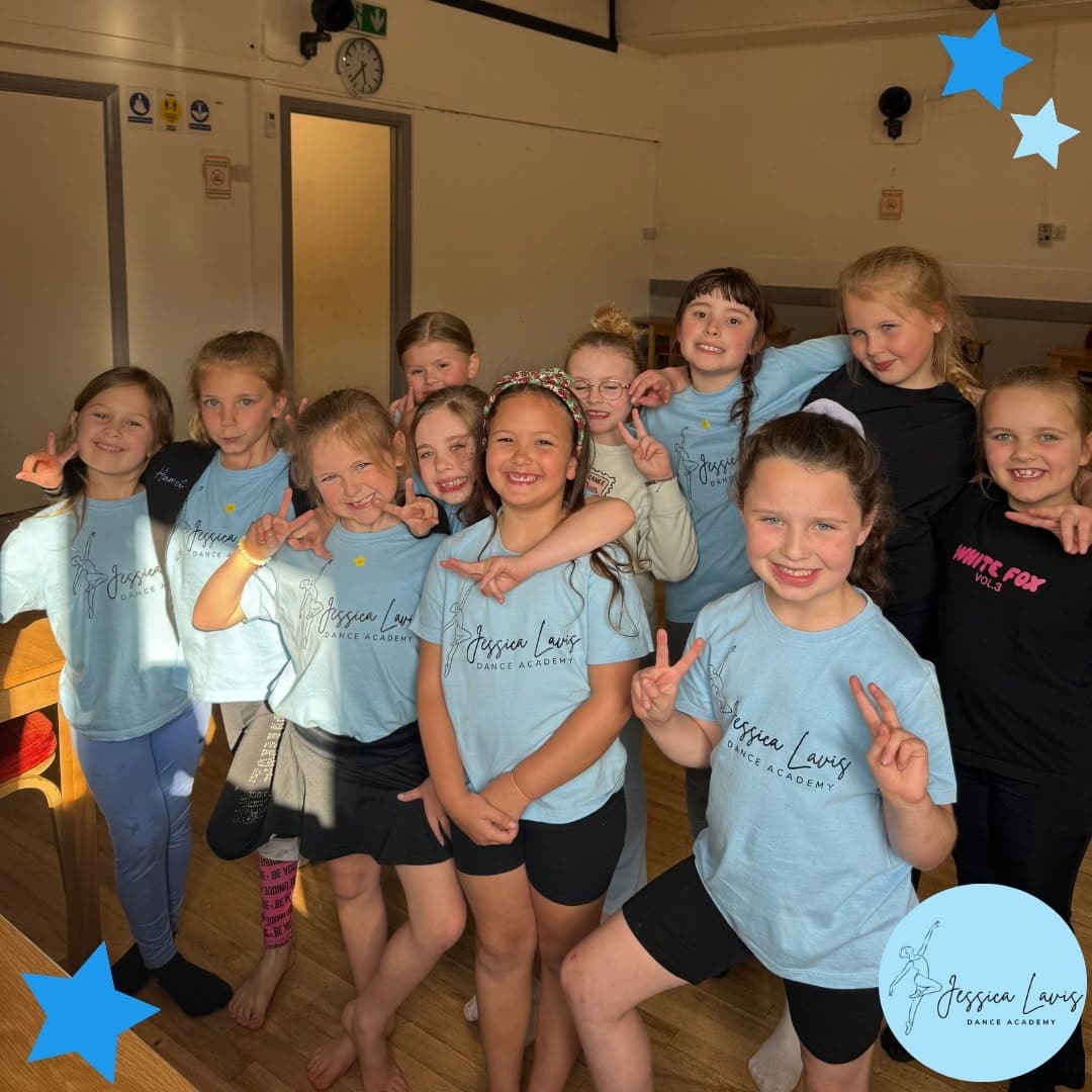 A big group of dancers grinning and flashing peace signs after class