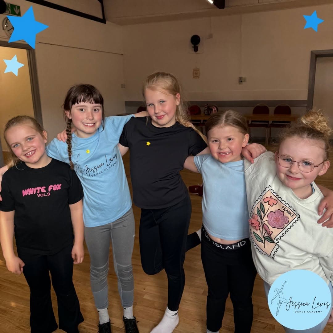 Junior dancers arm in arm in the studio after class