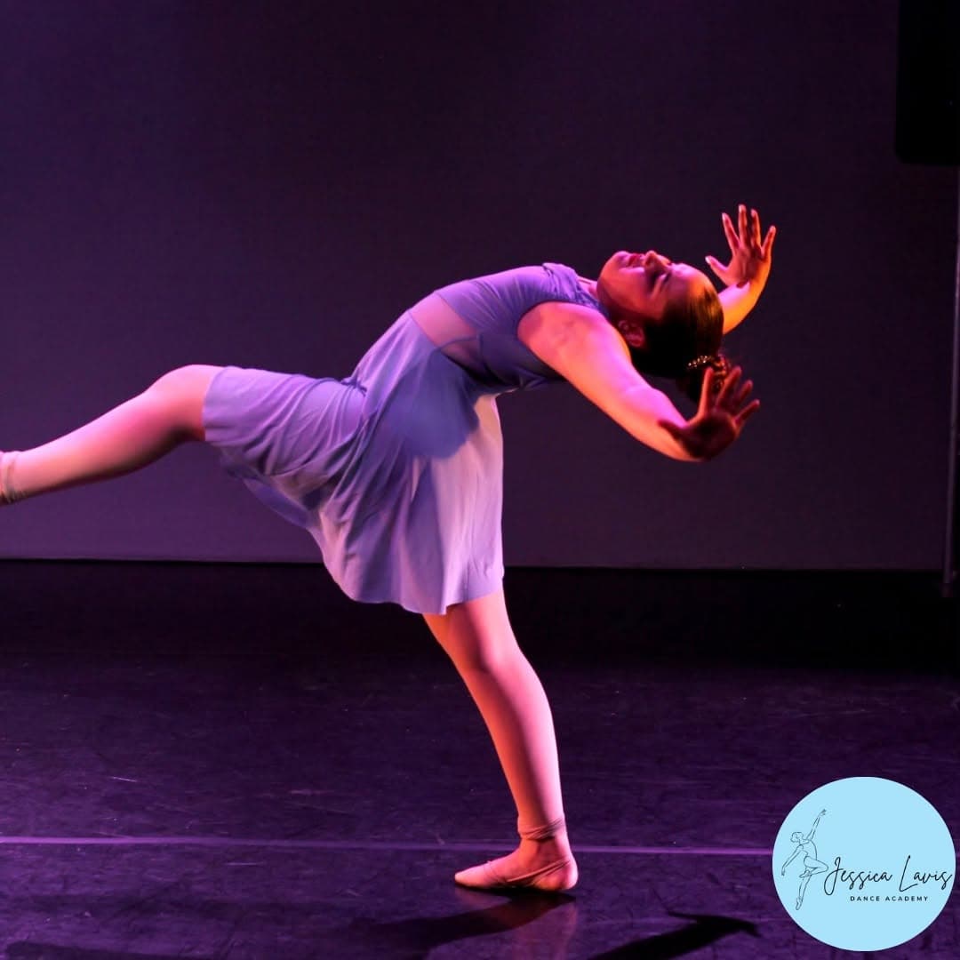 A young JLDA dancer in a lilac dress performing a graceful backbend on stage