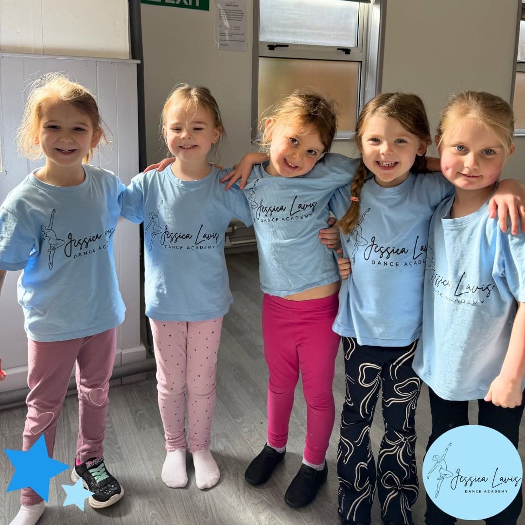 Five mini dancers in light blue JLDA t-shirts standing arm in arm and smiling
