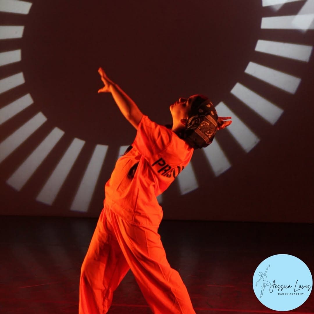 A soloist reaching skyward in dramatic orange light in front of a sunburst backdrop